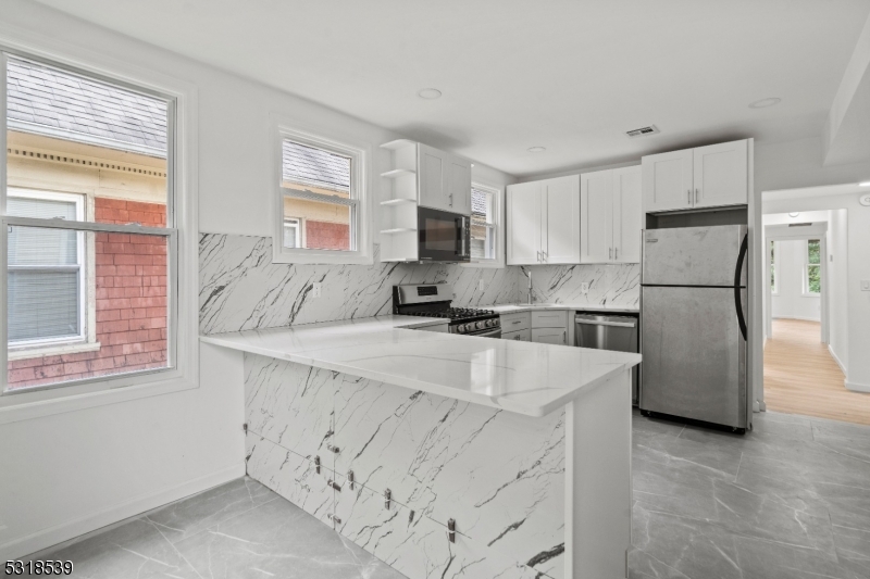 a kitchen with stainless steel appliances granite countertop a refrigerator sink stove and white cabinets