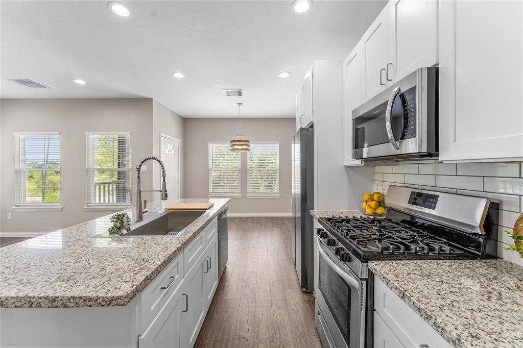 a kitchen with stainless steel appliances granite countertop a sink stove and cabinets