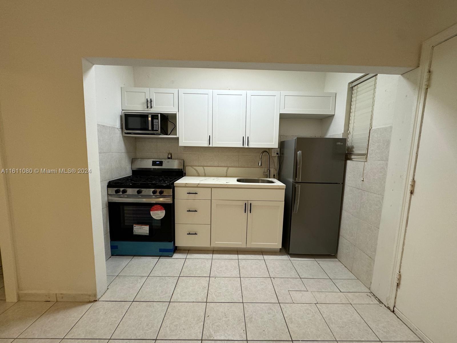 a kitchen with a refrigerator a stove a sink and cabinets