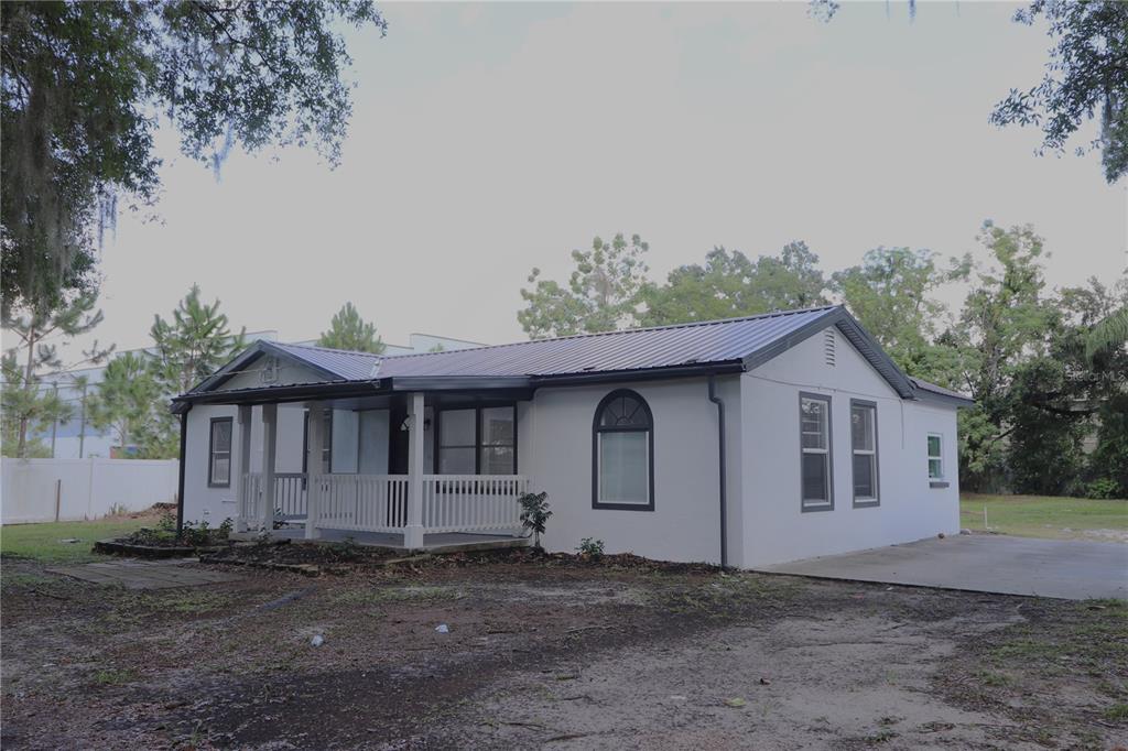 a view of a grey house with a yard and large trees