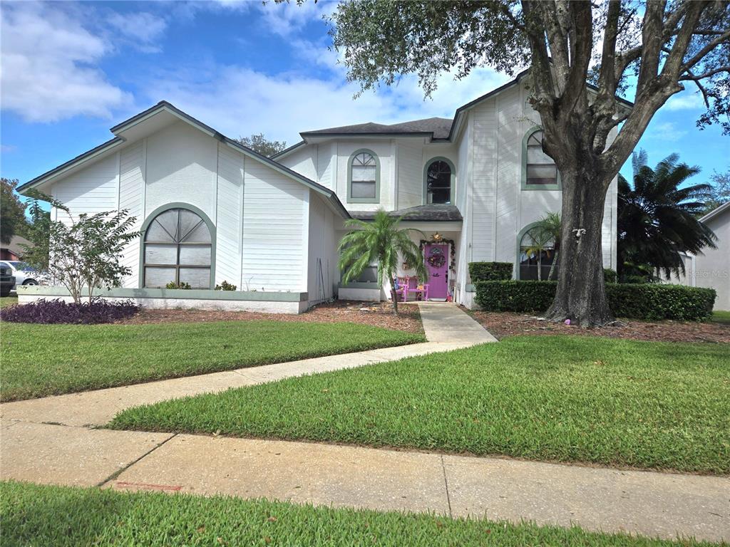 a view of a house with a small yard plants and a large tree