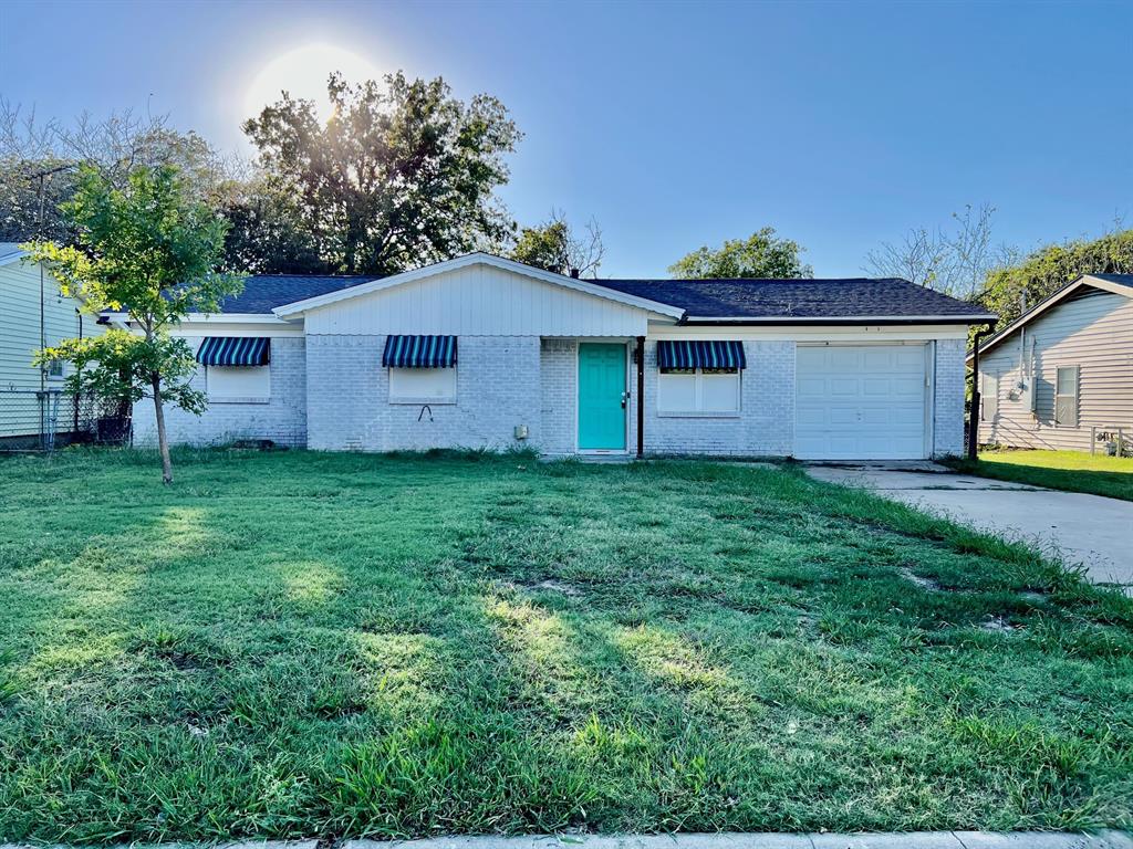 a house that is sitting in the grass with large trees and plants