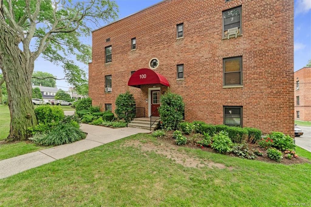 a view of a brick house with a yard and plants