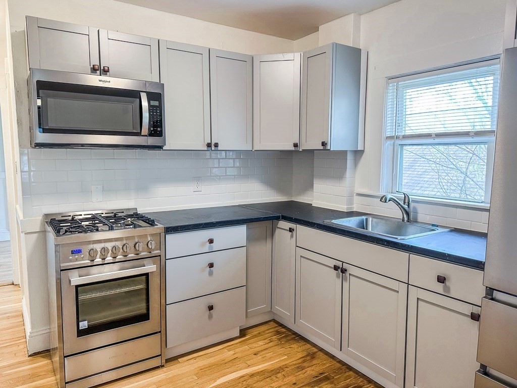 a kitchen with white cabinets and appliances