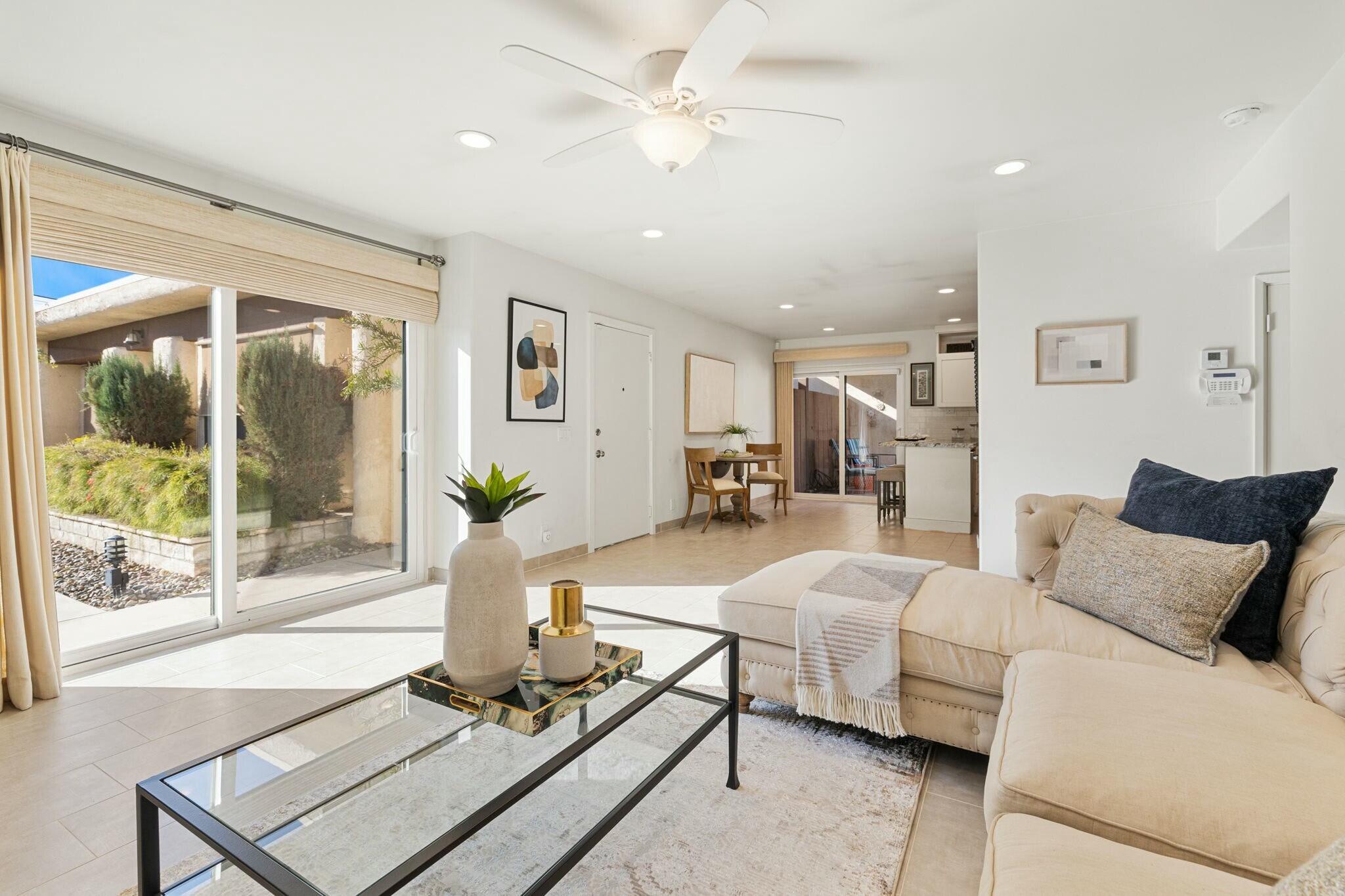 a living room with furniture a large window and potted plants