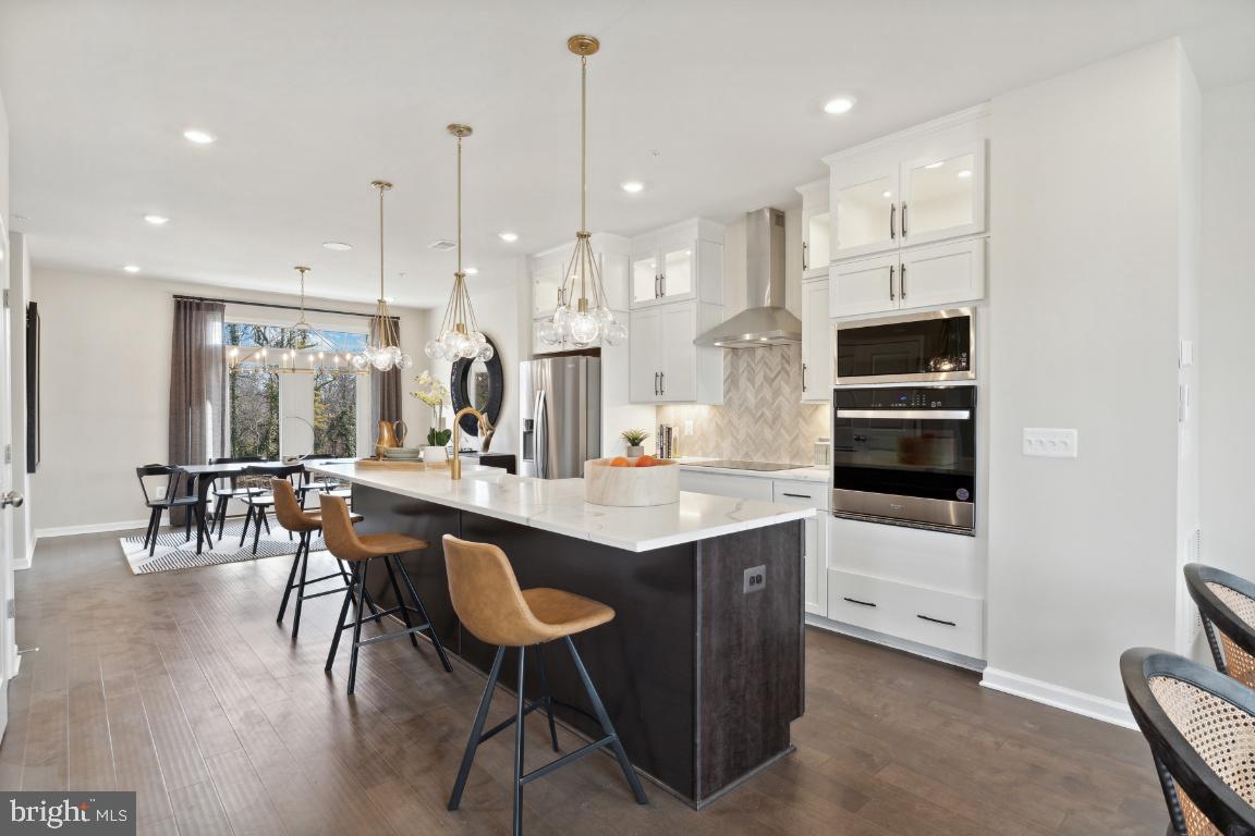 a kitchen with stainless steel appliances kitchen island granite countertop a table chairs sink and cabinets