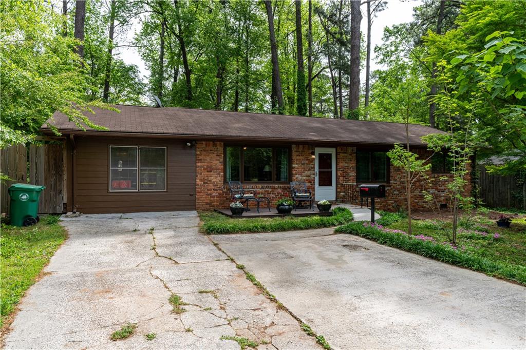 a view of a barn house in front of a yard with plants and large trees