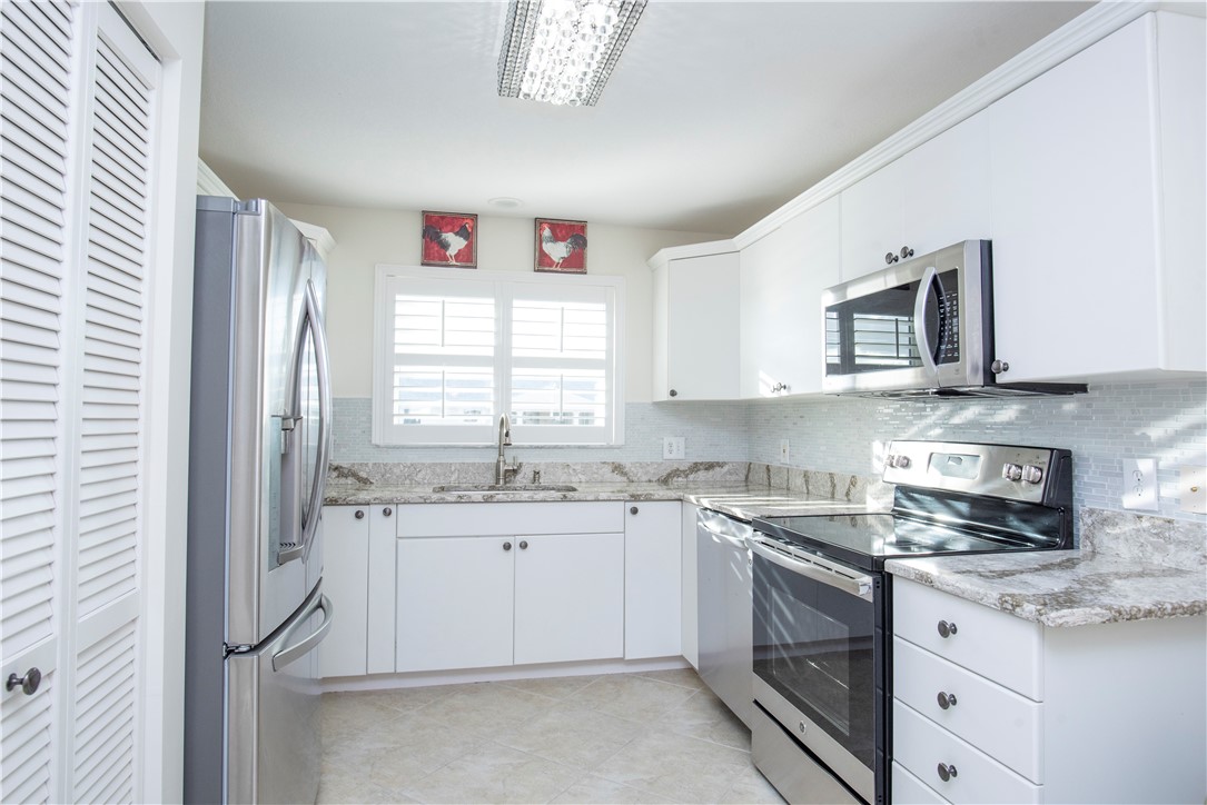 a kitchen with stainless steel appliances granite countertop a sink and dishwasher a stove top oven with white cabinets