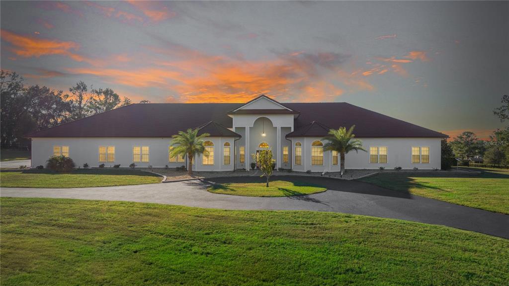 a view of a white house with a swimming pool and a yard