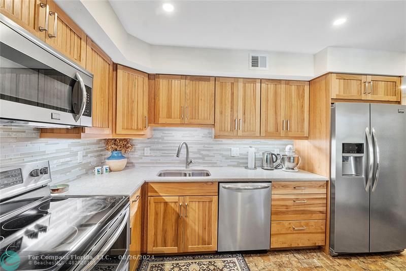 a kitchen with stainless steel appliances granite countertop a sink a stove and a refrigerator