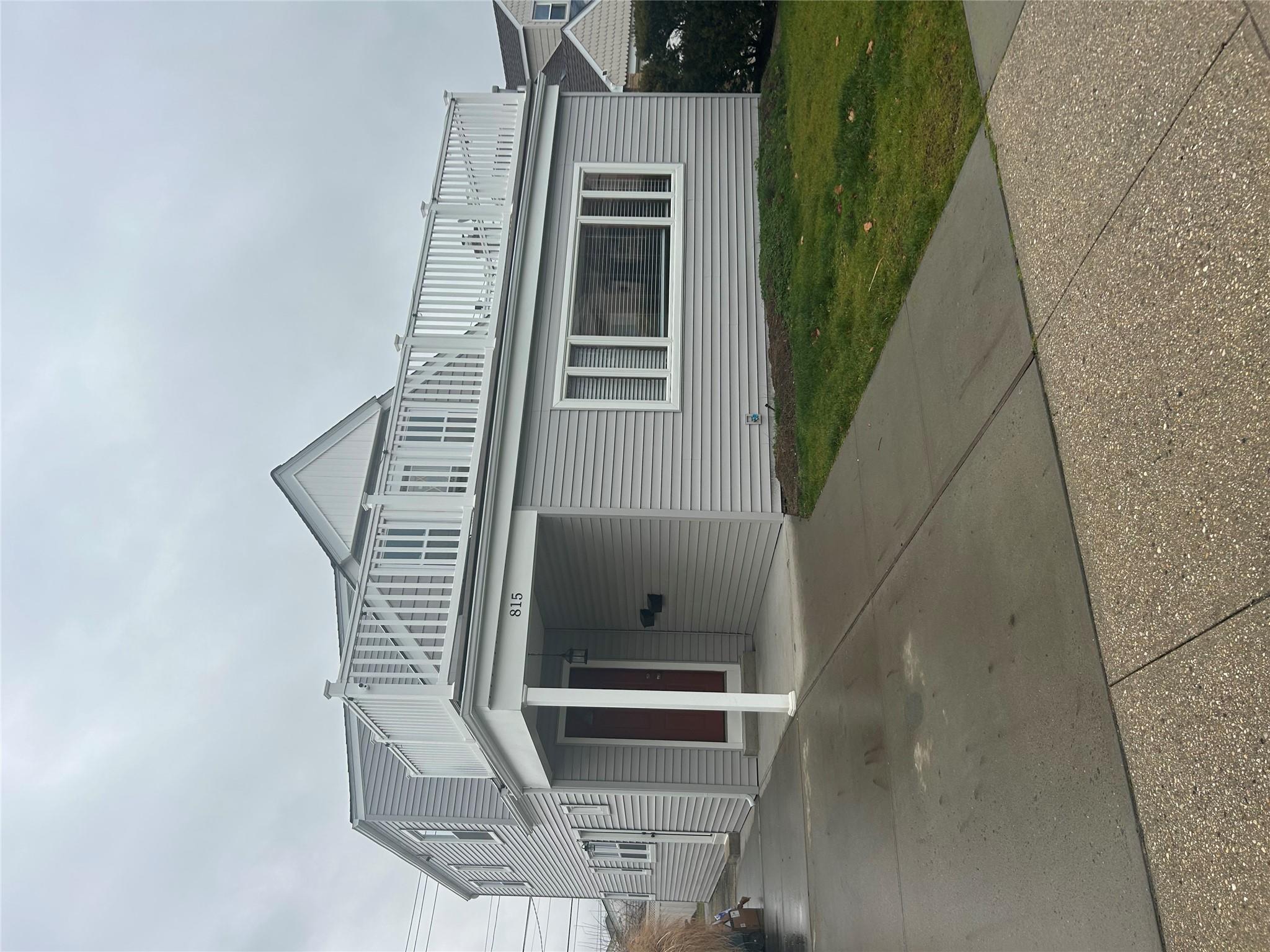 View of property exterior with a balcony, a carport, and a lawn