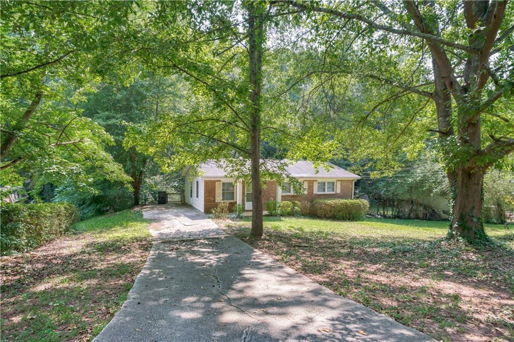 a front view of a house with a yard and large trees