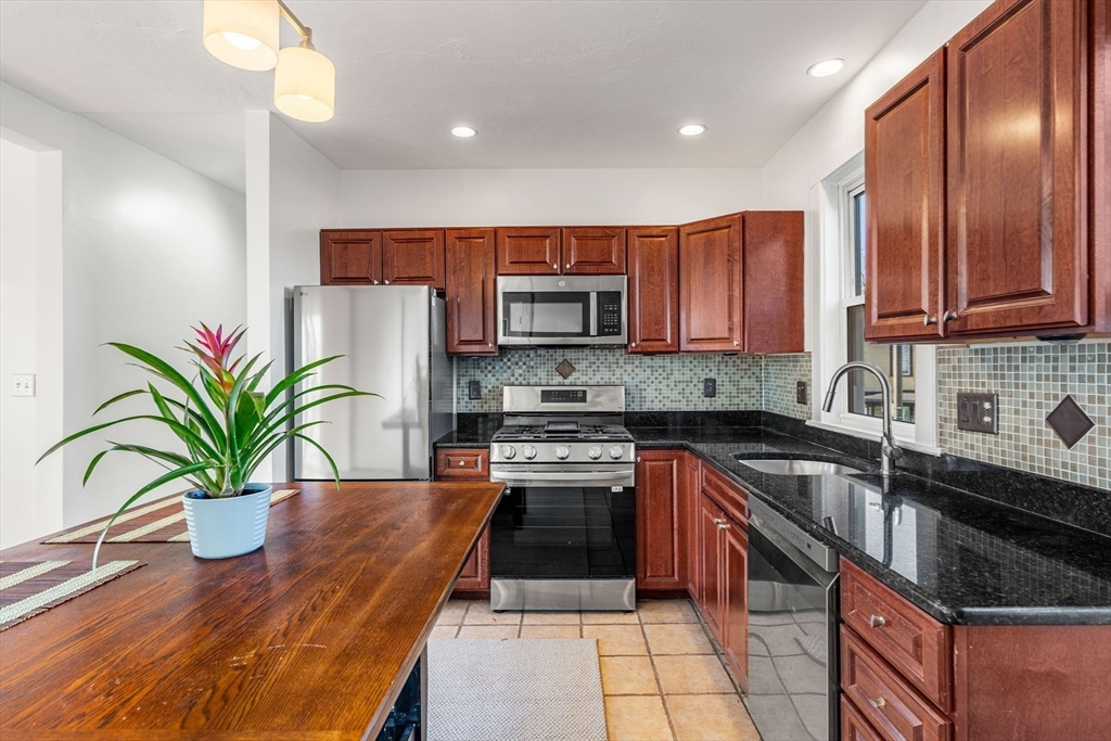 a kitchen with granite countertop a stove a sink and a microwave