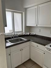 a kitchen with granite countertop white cabinets and a sink