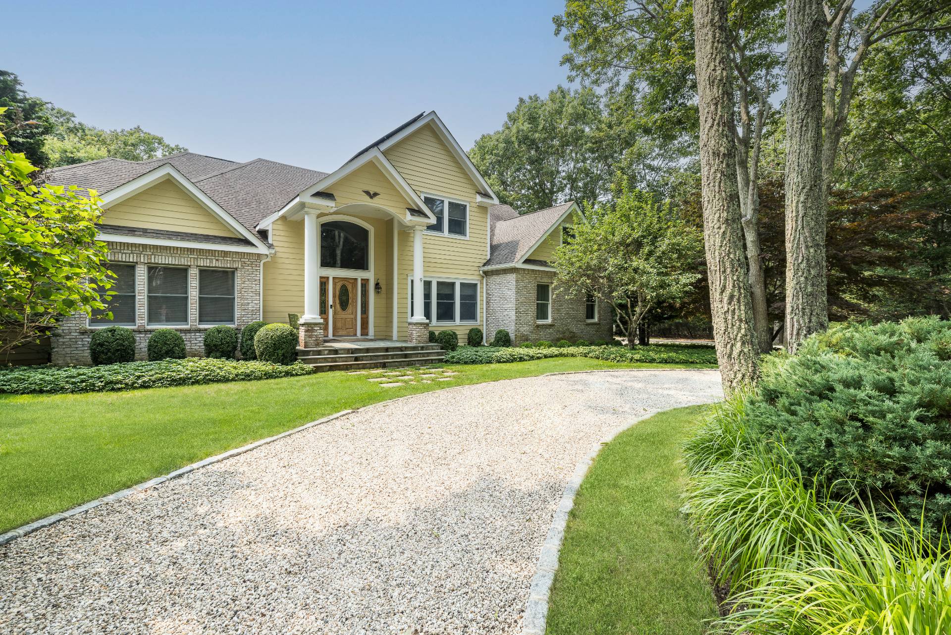 a view of a house with a big yard plants and large trees