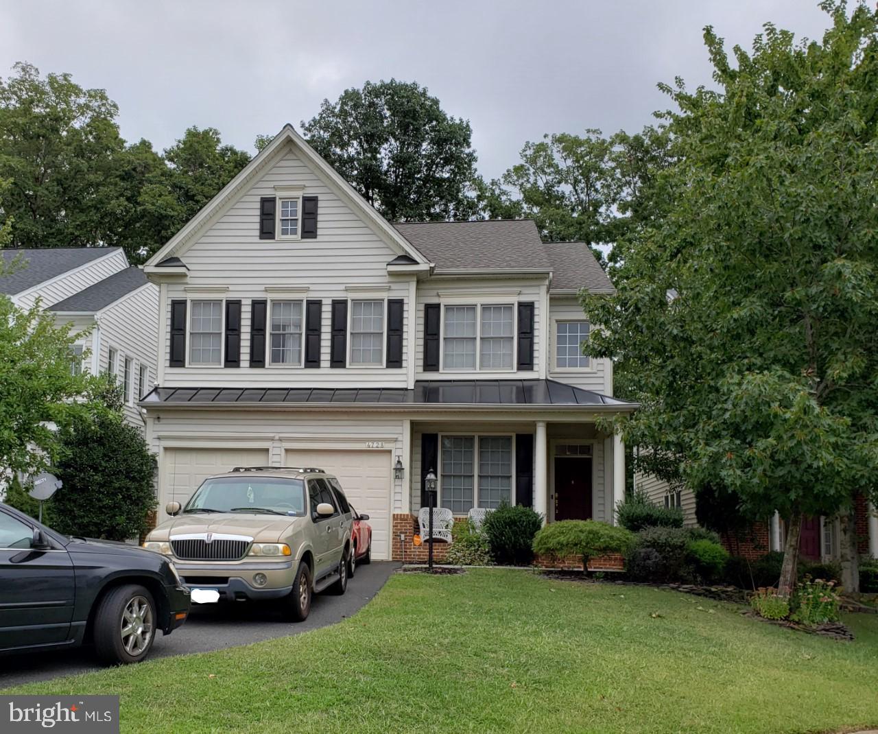 a front view of a house with a garden and trees