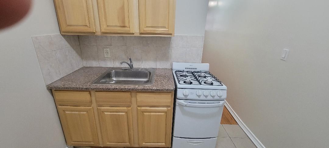 Kitchen featuring backsplash, light tile patterned flooring, sink, and white range with gas cooktop