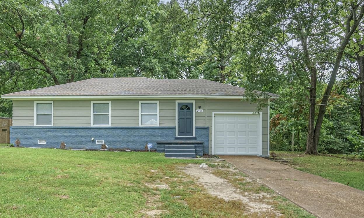 Single story home with a garage and a front lawn