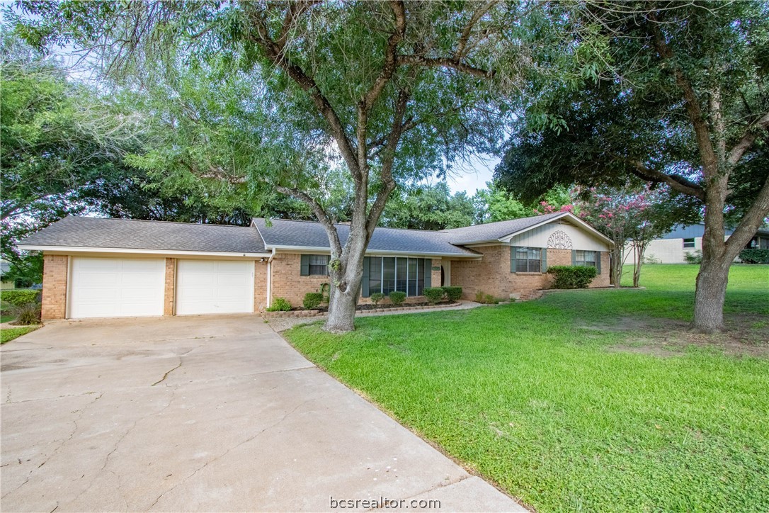 front view of a house with a yard and large trees