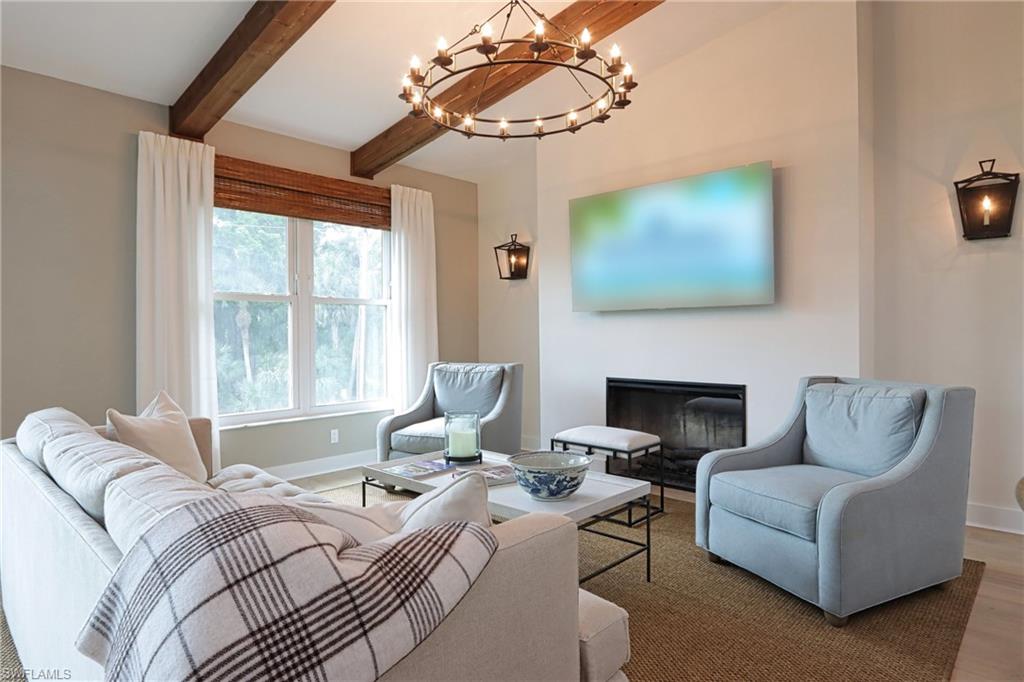 Living room with hardwood / wood-style floors, lofted ceiling with beams, and a notable chandelier