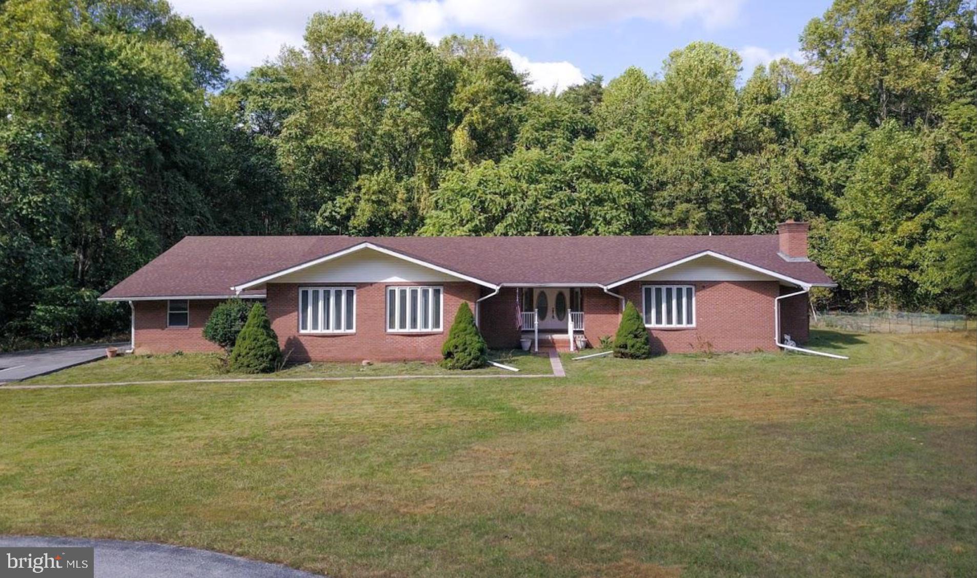 a view of a house with a big yard and large trees