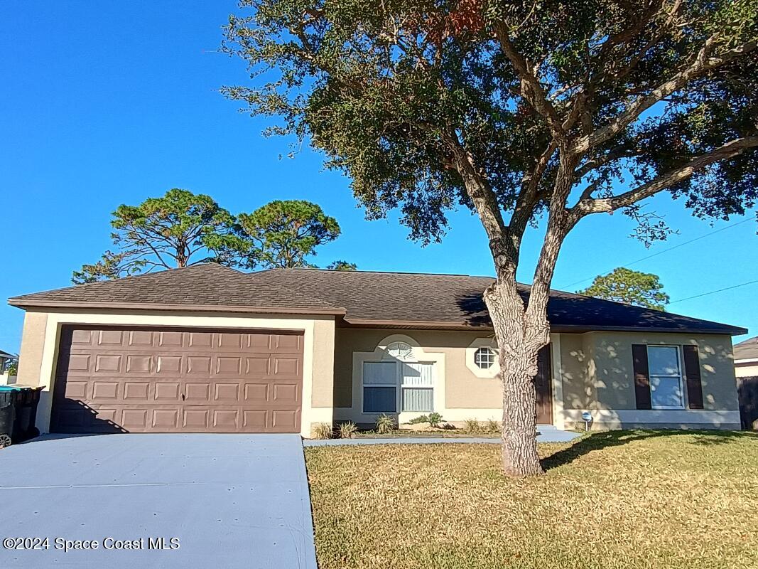 a front view of a house with a tree in a yard