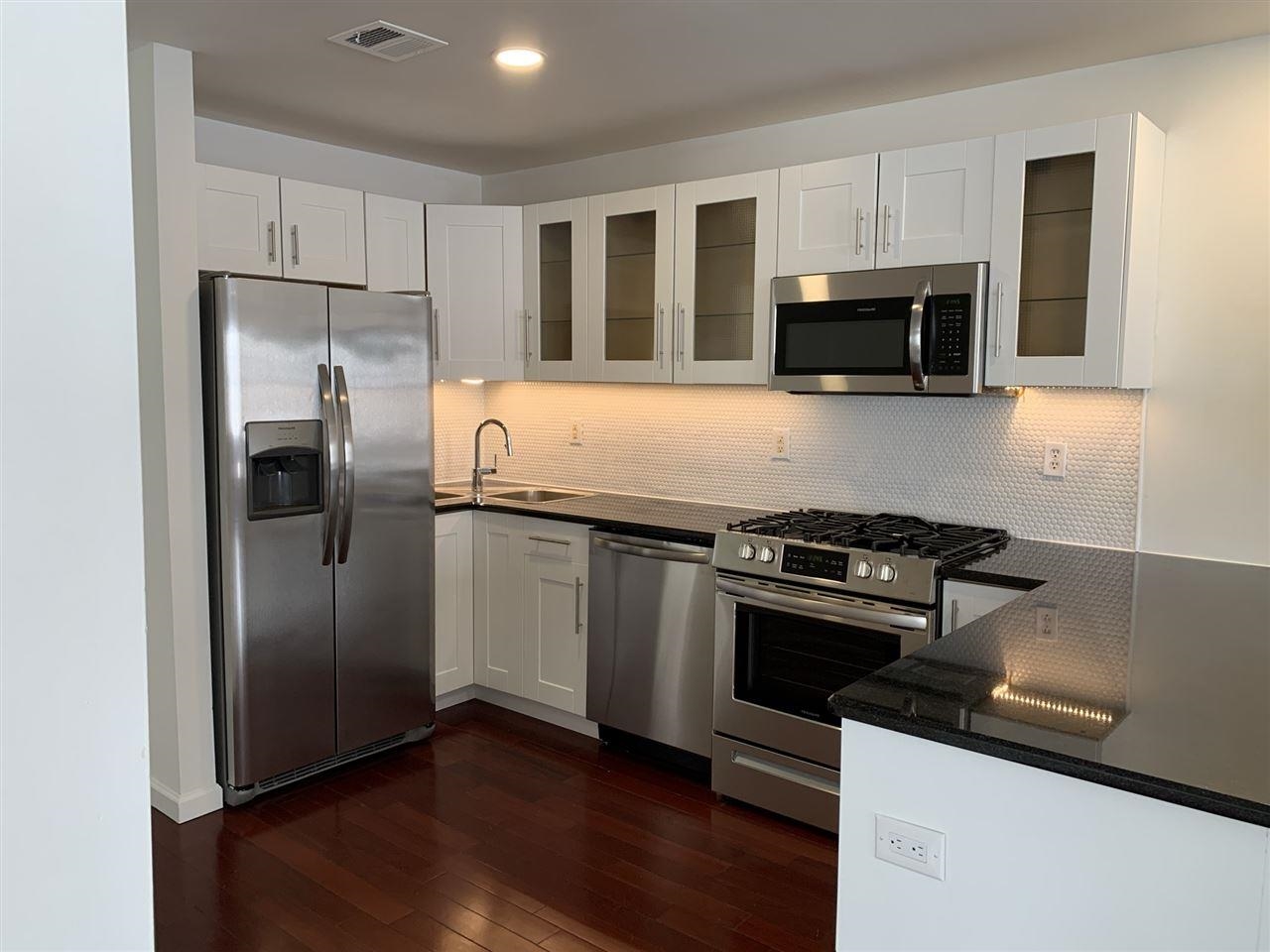 a kitchen with stainless steel appliances granite countertop a refrigerator microwave and sink