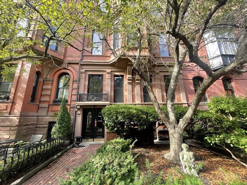 front view of a brick house with a large tree