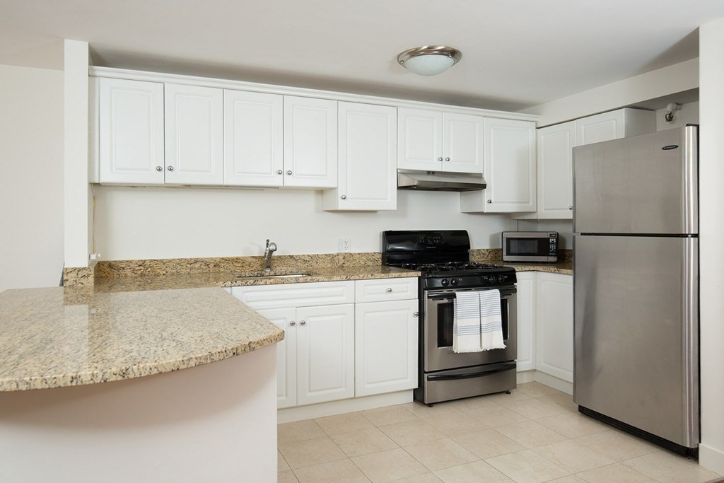 a kitchen with kitchen island granite countertop white cabinets and refrigerator