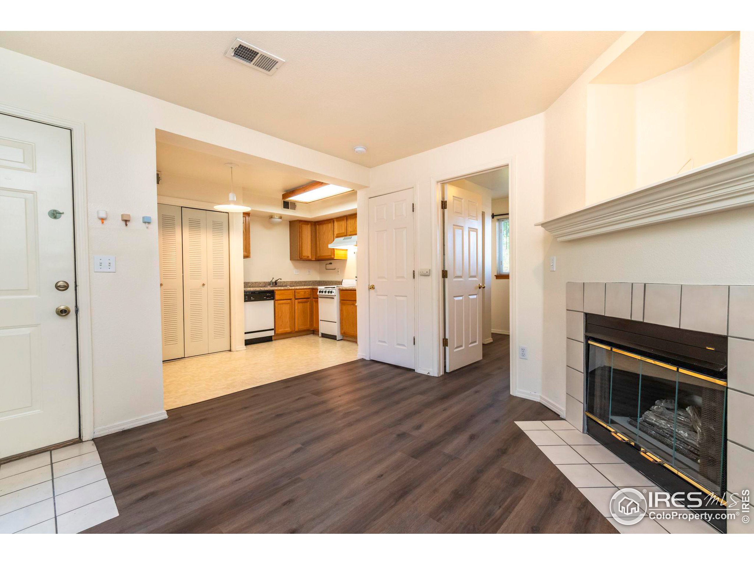 a view of kitchen and empty room with wooden floor