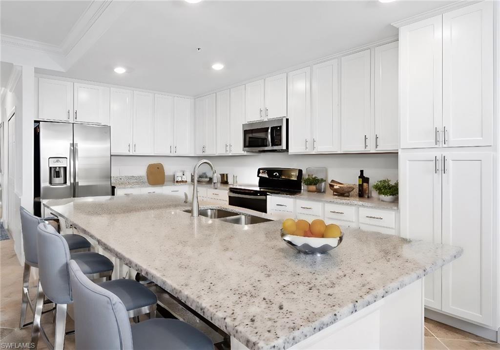 a kitchen with stainless steel appliances granite countertop a sink refrigerator and white cabinets