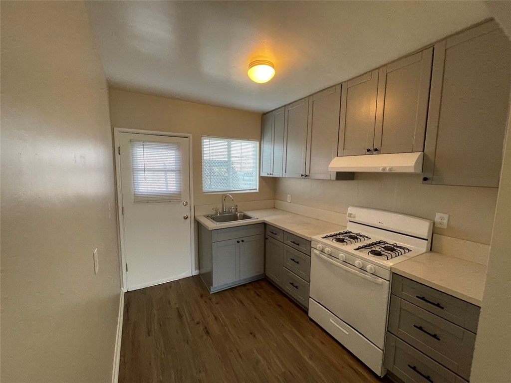 a kitchen with granite countertop a stove a sink and a microwave