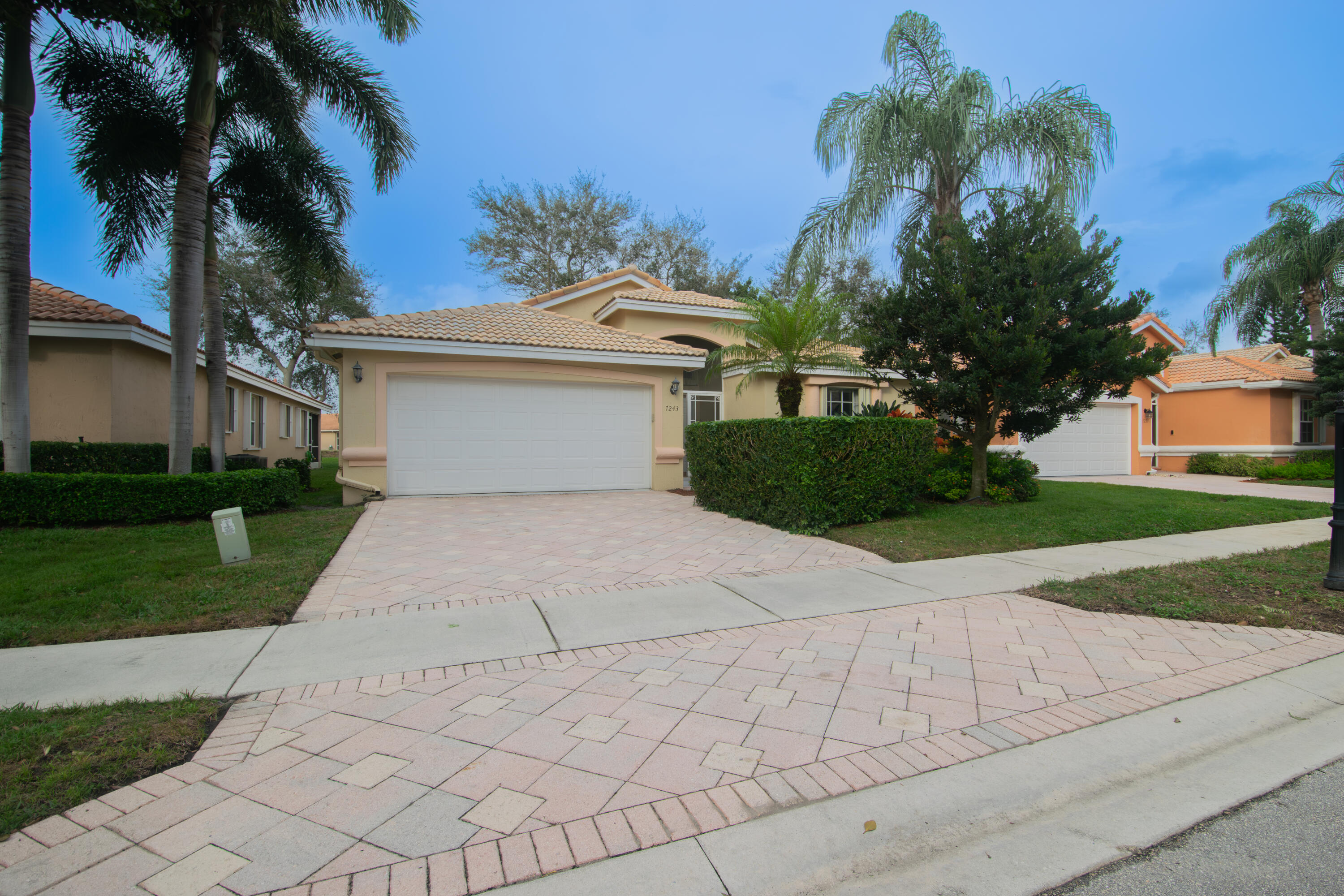 a front view of a house with a yard and palm trees