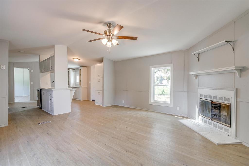 a view of a livingroom with a fireplace a ceiling fan and wooden floor