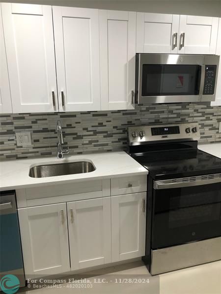 a kitchen with granite countertop a stove microwave and sink