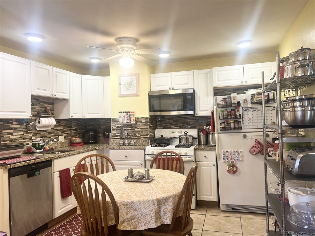 a kitchen with granite countertop a stove a sink a dining table and chairs