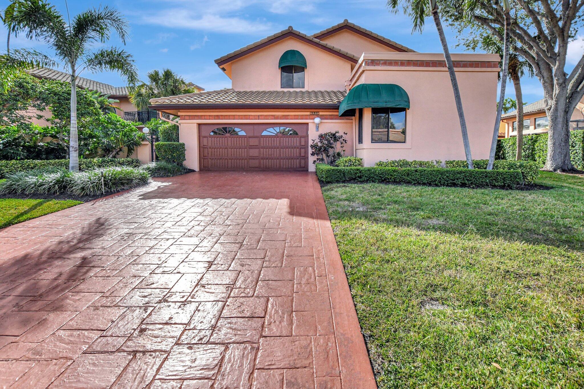 a front view of a house with a yard and potted plants