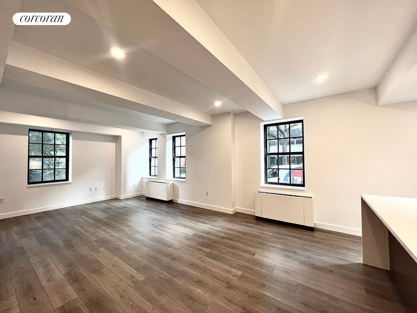 a view of an empty room with a window and wooden floor