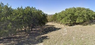 a view of a dirt road with trees in the background