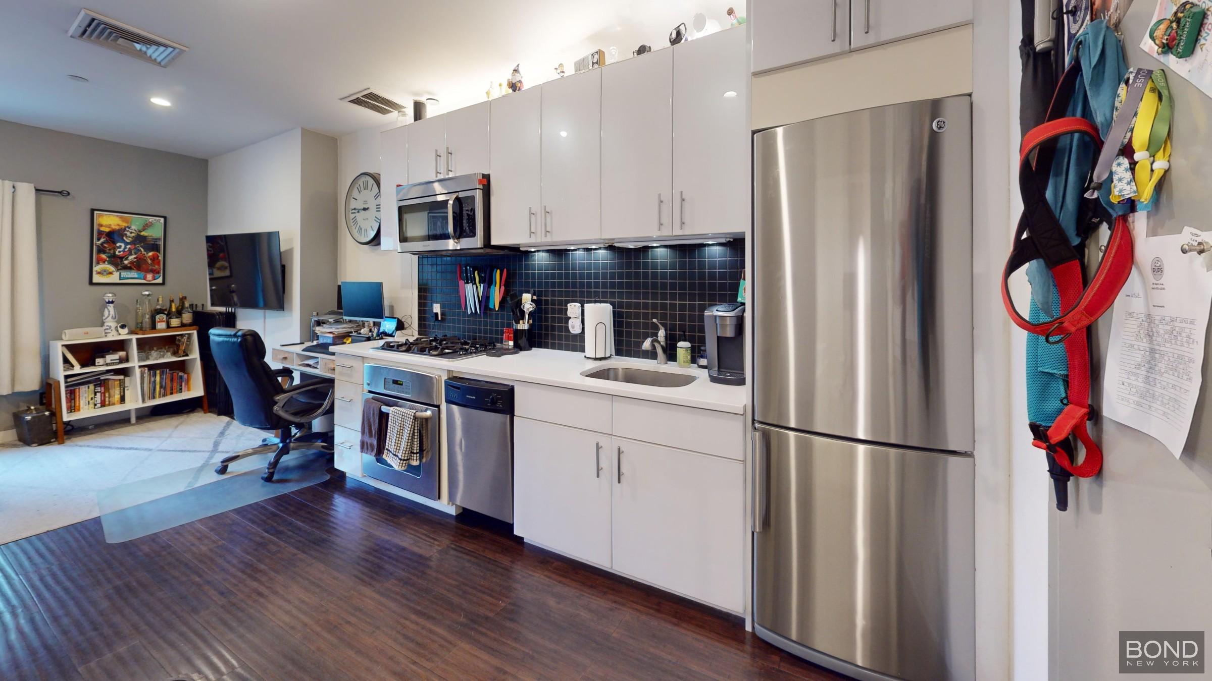 a kitchen with stainless steel appliances granite countertop a refrigerator and a stove with wooden floor