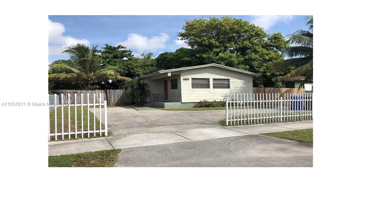 a view of a house with a small yard and wooden fence