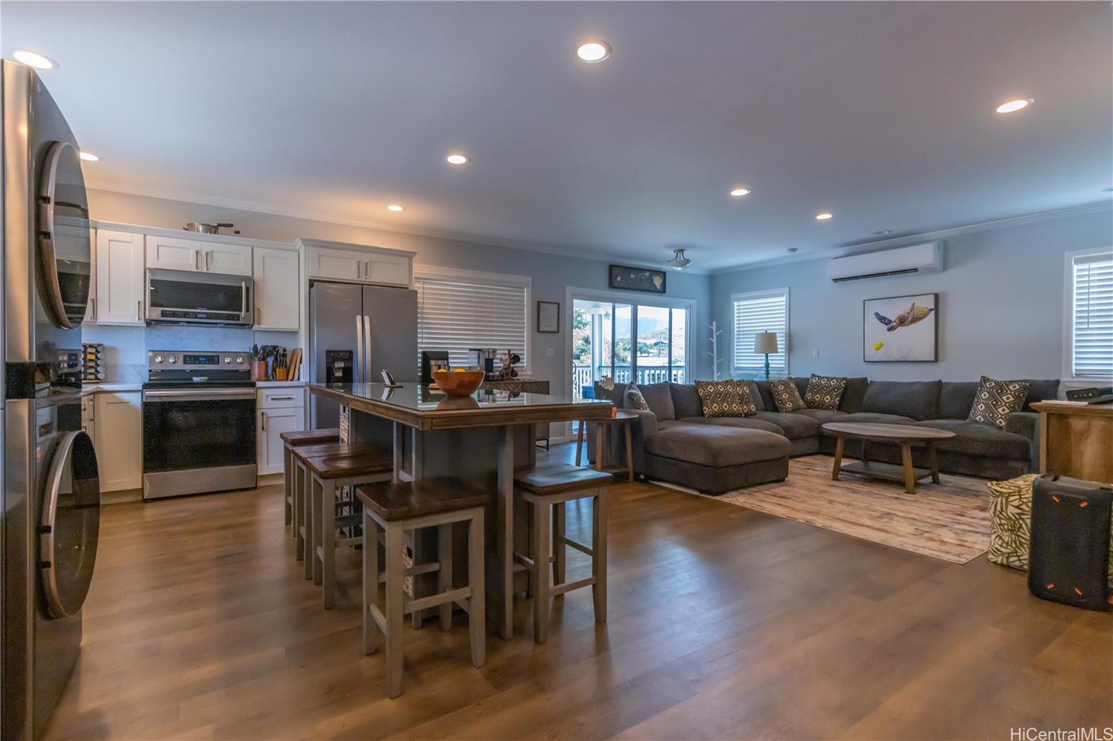 a living room with furniture a flat screen tv and kitchen view