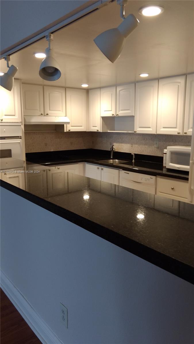 a kitchen with stainless steel appliances a sink cabinets and a wooden floor