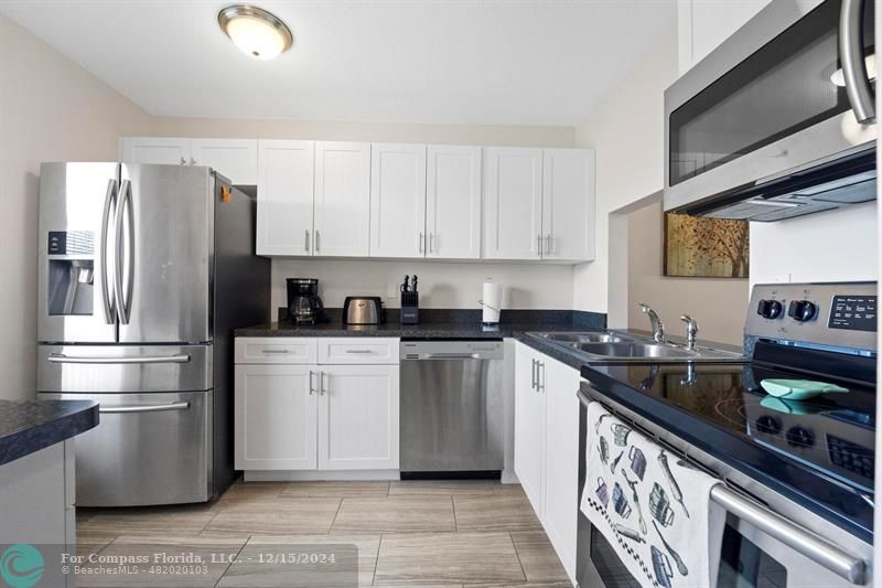 a kitchen with stainless steel appliances granite countertop a refrigerator sink and stove