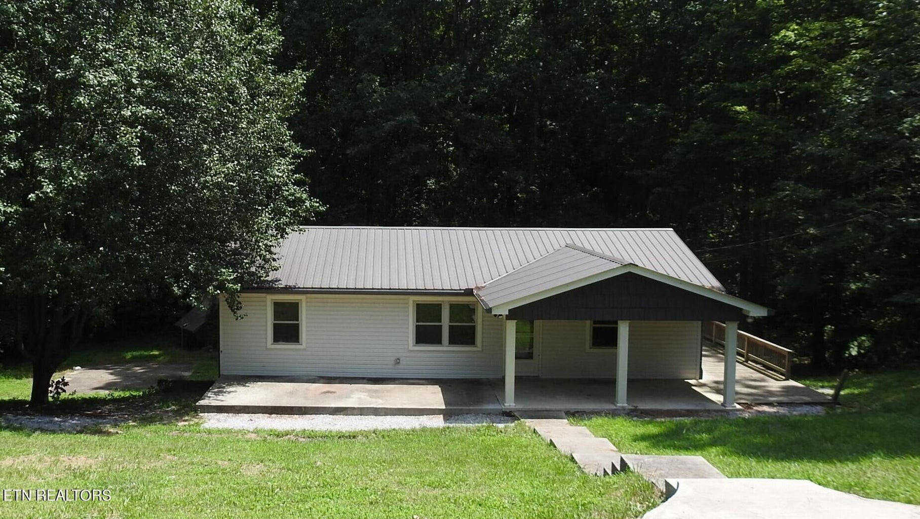 a front view of a house with a garden and trees