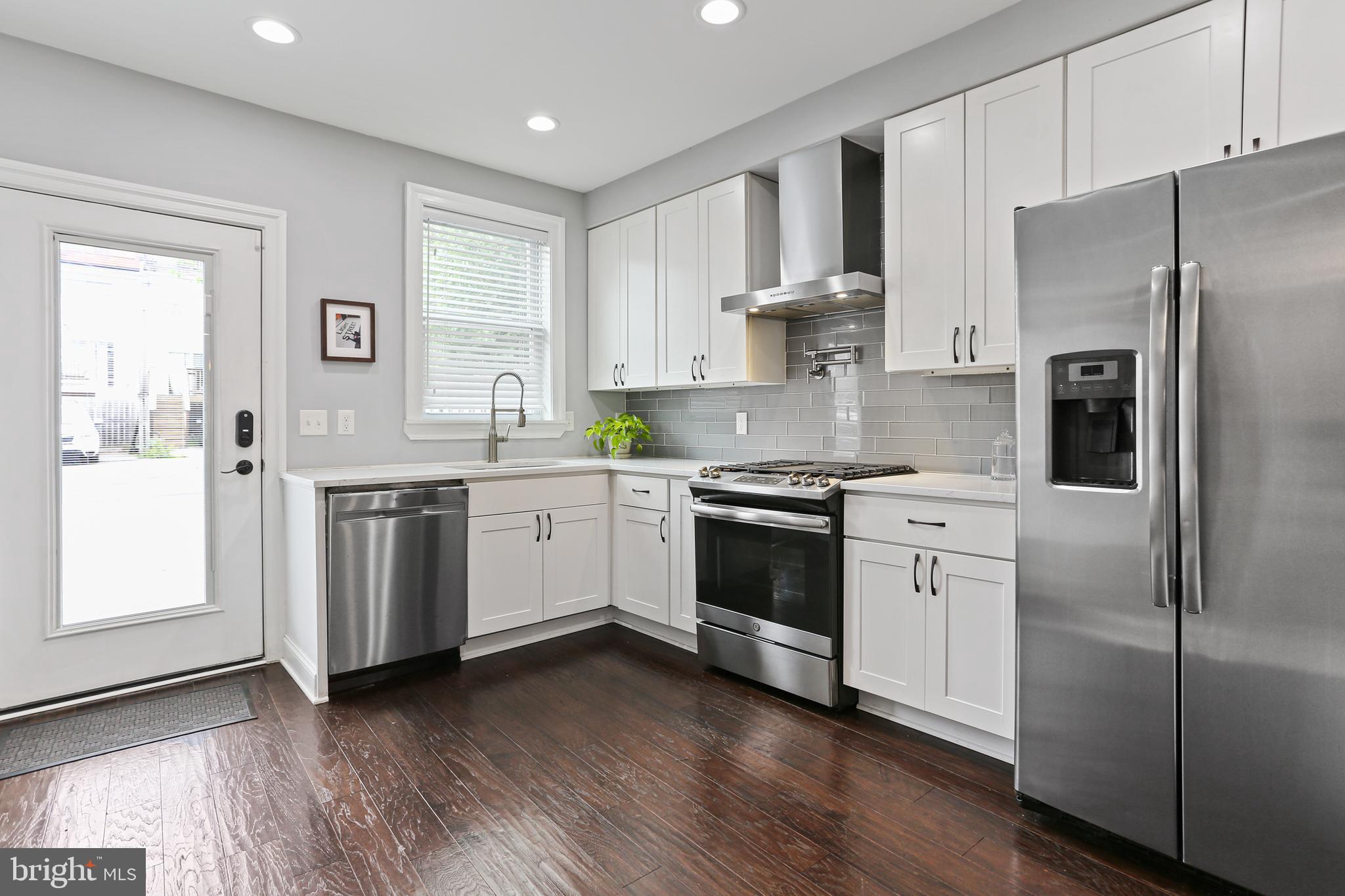 a kitchen with white cabinets stainless steel appliances and wooden floor