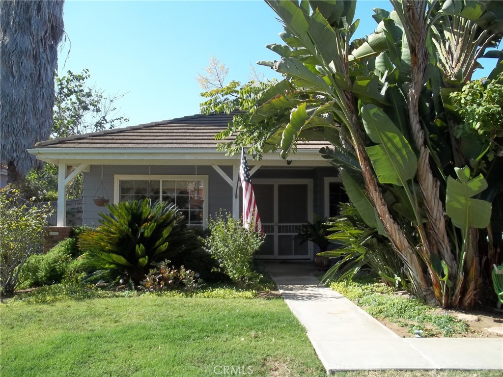 a view of house with a yard and potted plants