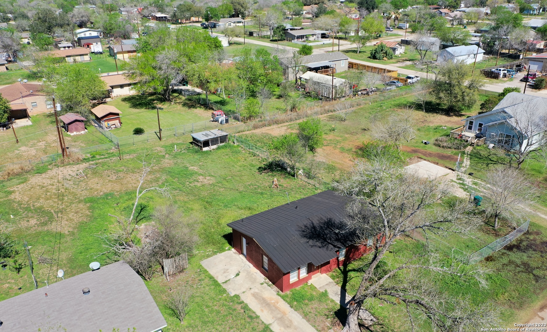 an aerial view of residential houses with outdoor space and trees