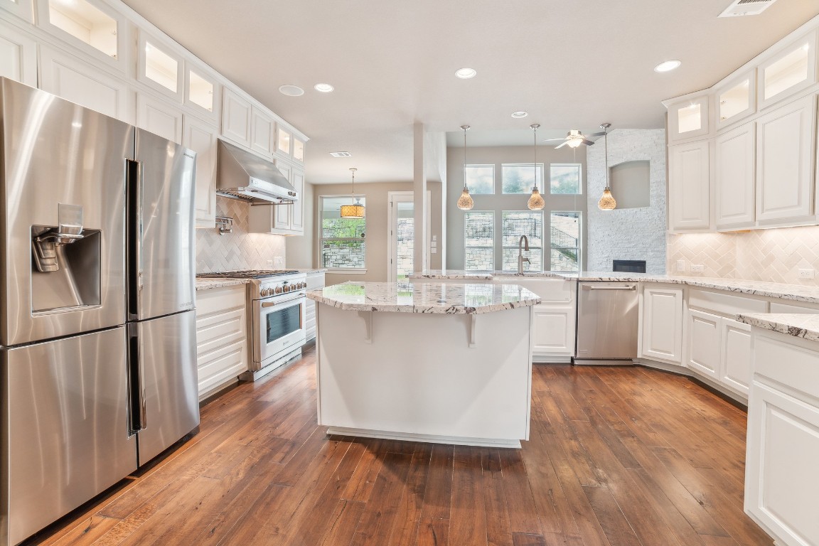 a large kitchen with a center island wooden floor stainless steel appliances and windows