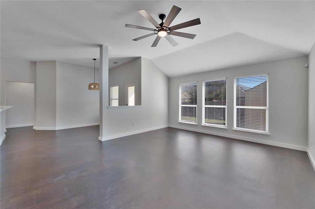 a view of an empty room with a window and wooden floor